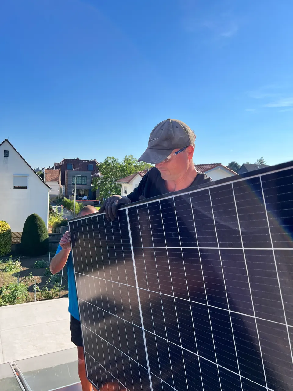 Monteur trägt Solarmodul aufs Dach